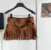 Brown fringe skirt on a hanger with a  bag in the background